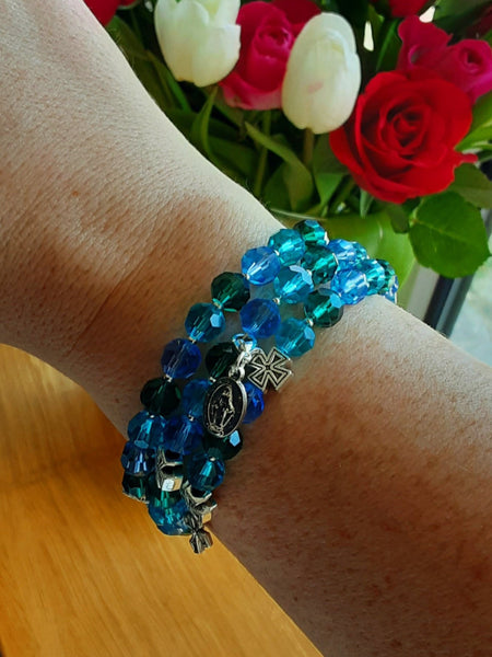 Blue and green beads. Rosary bracelet on arm. 